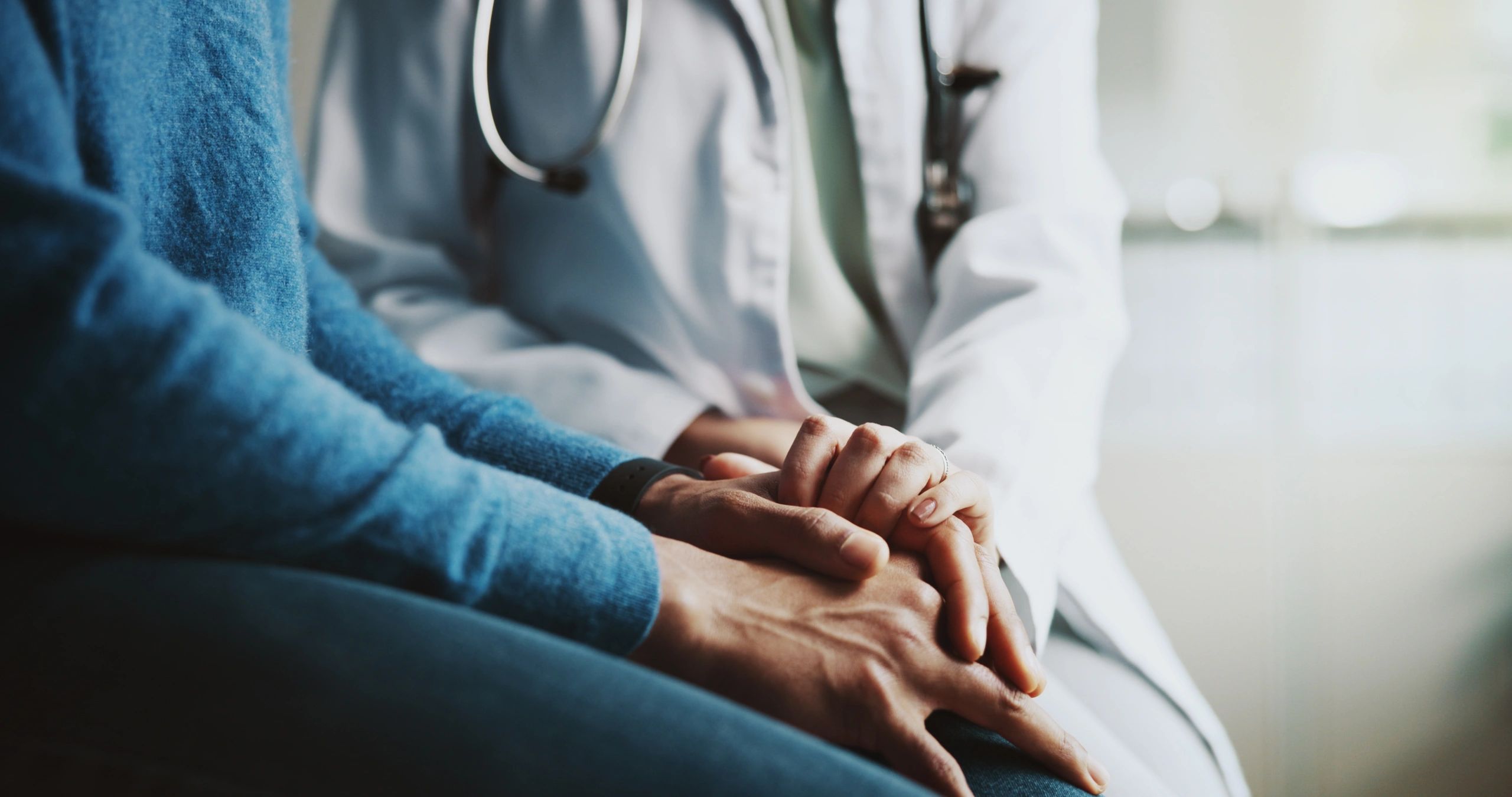 Doctor comforting a patient by holding hands.