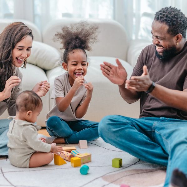A joyful family playing with blocks on the floor.
