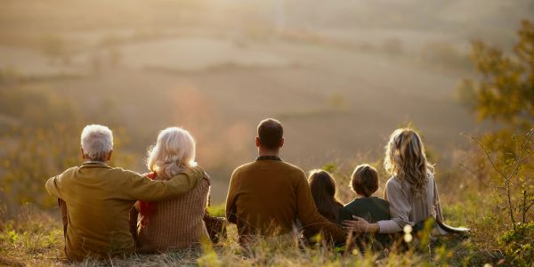 A family of six sitting outdoors, enjoying a scenic view together.
