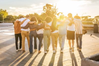Friends walking arm in arm at sunset, enjoying togetherness.