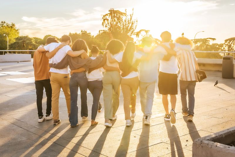 Students walking together with arms around each other, enjoying the sunset and embodying friendship, unity, and togetherness
