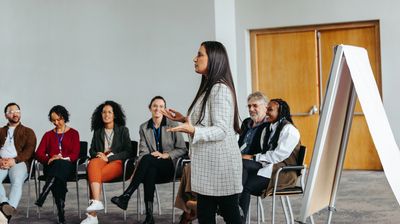 Woman presenting to a group in a meeting room.