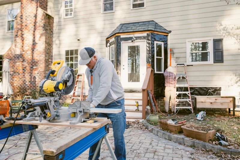 Father and son repair the siding of a colonial style house