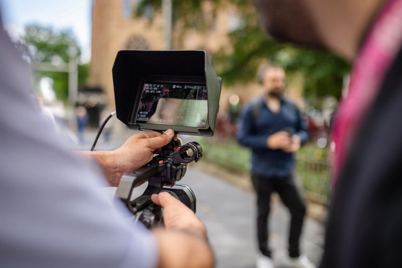 A video production crew captures a scene in Sydney, Australia. A person stands in the background while the camera operator adjusts equipment for a professional shoot.