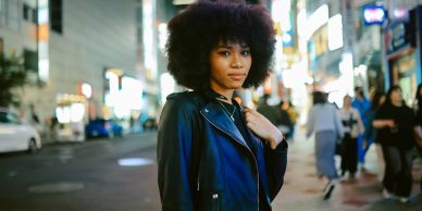 Confident woman with afro hairstyle in a city at night.