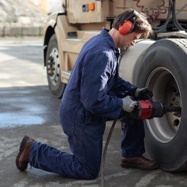 Mechanic fixing a truck tire outdoors.