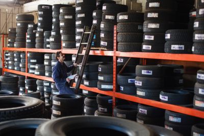 Worker organizing tires on high shelves in a tire store.