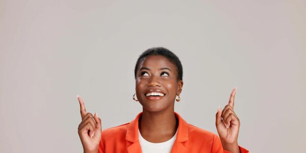 Happy woman pointing upwards with both hands.