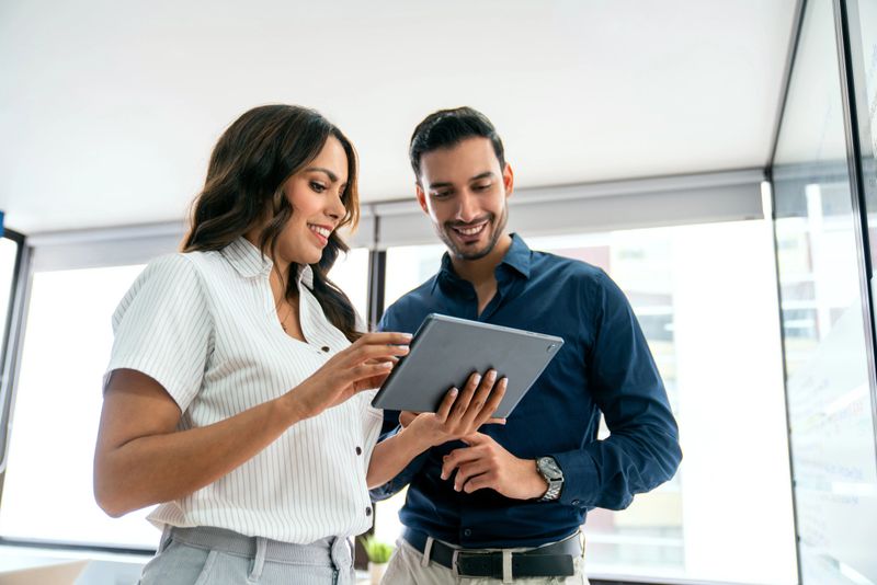 Latin American business people sharing ideas at the office while using a digital tablet - people at work concepts