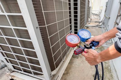 Person checking air conditioner pressure with gauges.