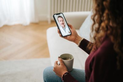 Person video chatting on a smartphone while relaxing on a couch.