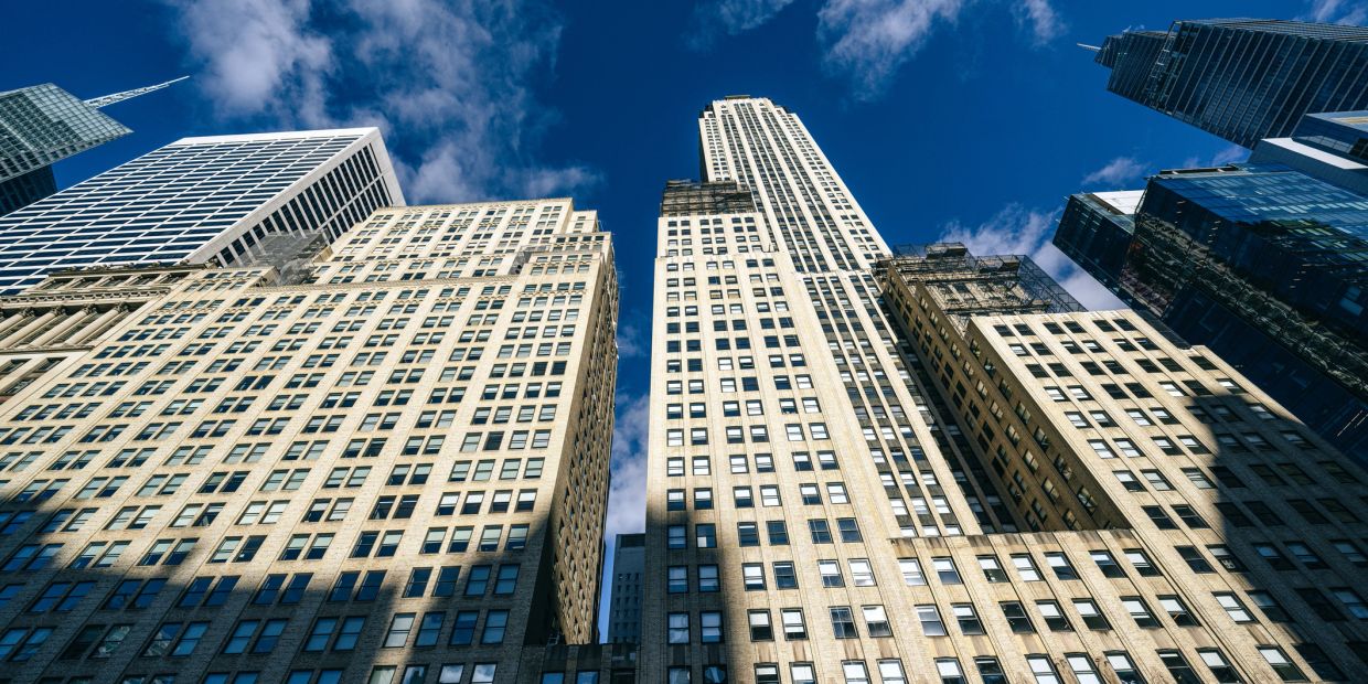 Upward view of tall city skyscrapers against a blue sky.