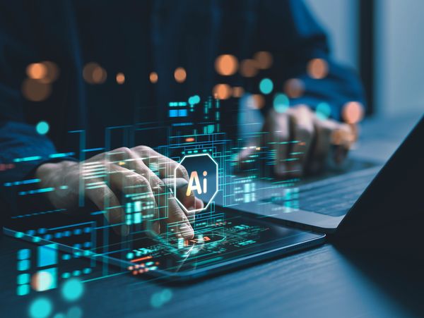 Hands typing on a laptop with a glowing digital overlay showing "AI" inside a hexagonal network 