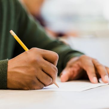 Person writing with a pencil on paper.