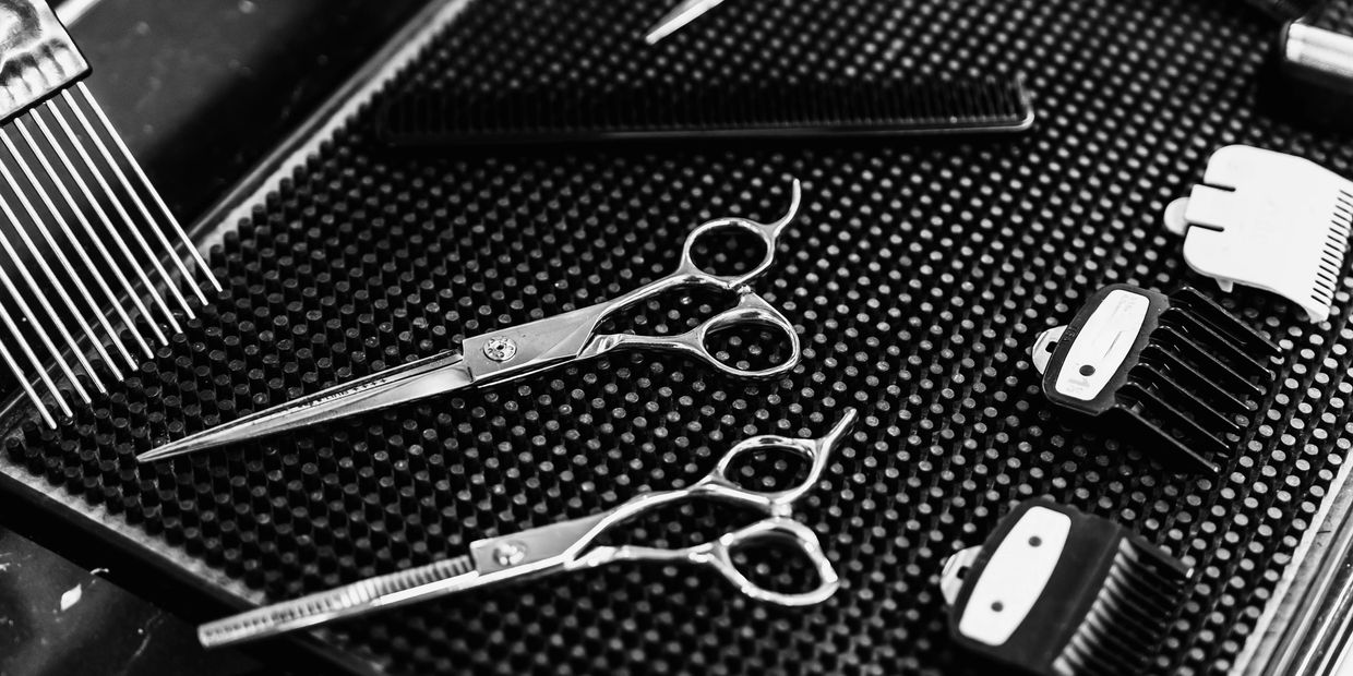 Hairdressing scissors and comb attachments on a textured mat.