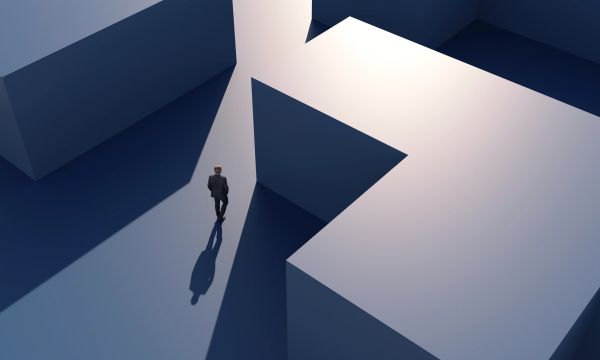 A person faces a large question mark structure.