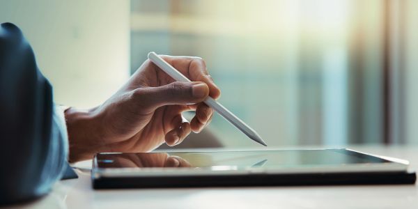 Person using stylus pen on a digital tablet in natural light.