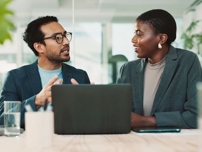 Professionals communicating in front of a laptop.