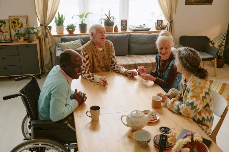 High angle shot of biracial company of elderly friends sitting at table chatting and enjoying tea time