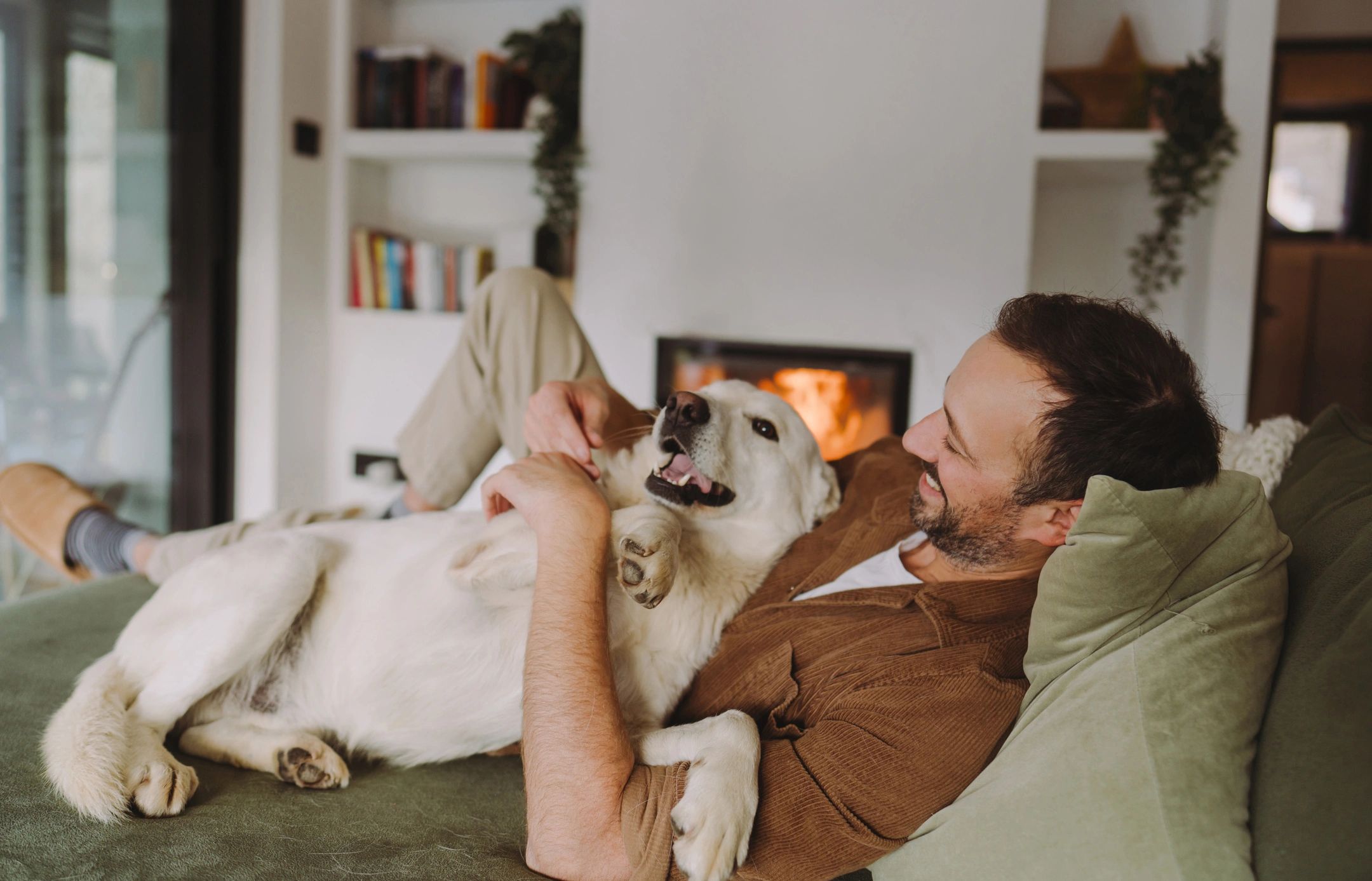Man lying on a couch happily cuddling with his dog.