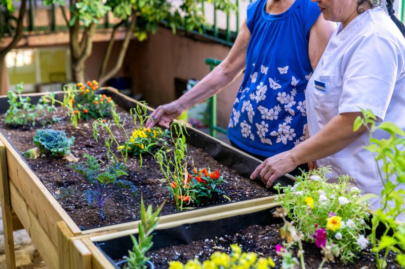 Senior adults engaging in therapeutic gardening at a nursing home, nurturing plants in raised beds for relaxation and well-being