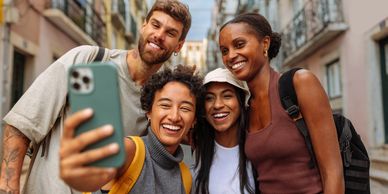 Four friends happily taking a selfie together on a city street.