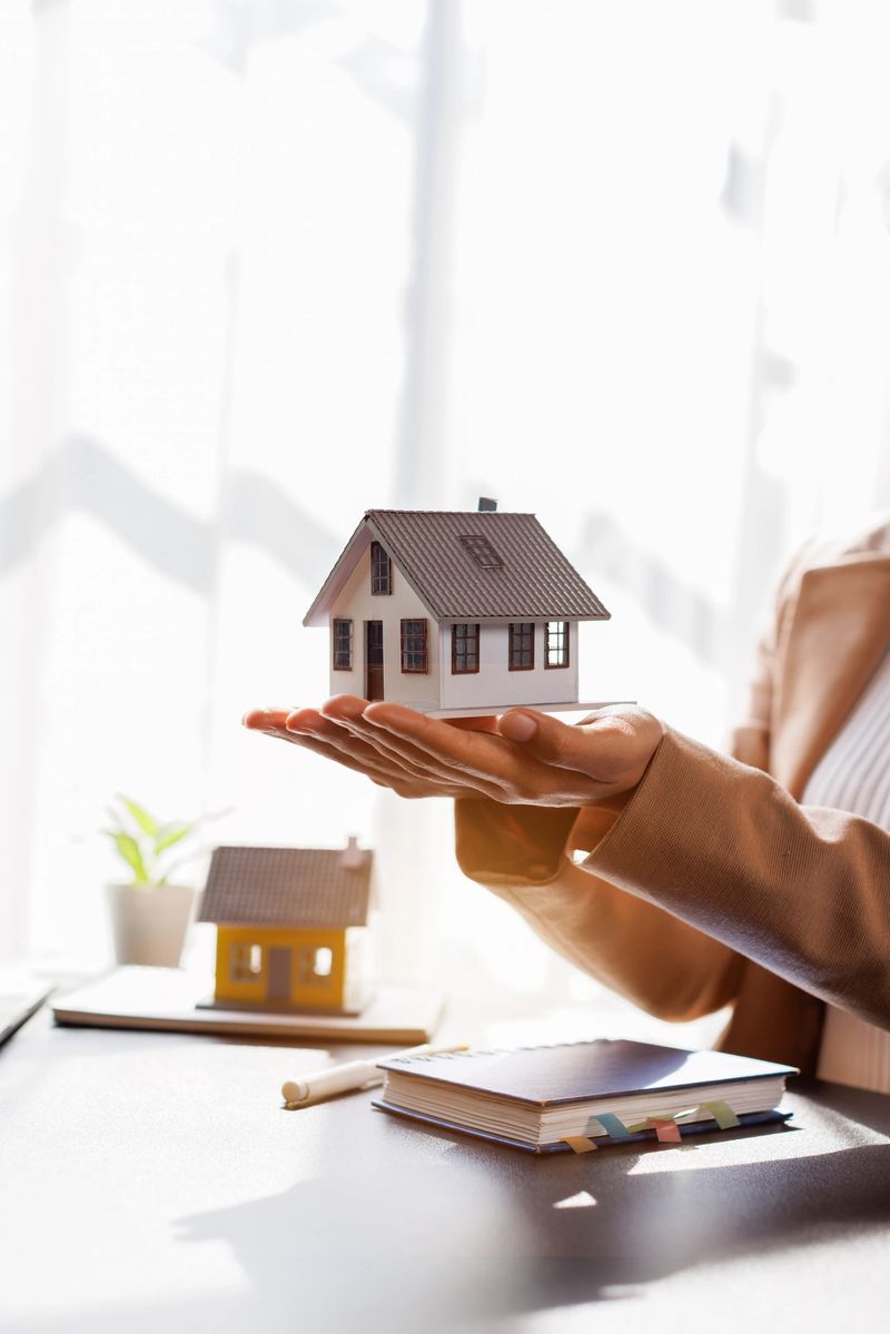 Hand of woman holding model house, real estate mortgage insurance and mortgage loan property insurance dream banking concept.