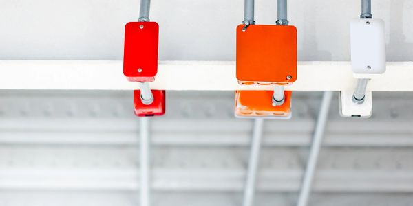 Three colored electrical junction boxes (red, orange, white) mounted on a ceiling.