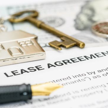 A lease agreement with a pen and a house-shaped keychain.