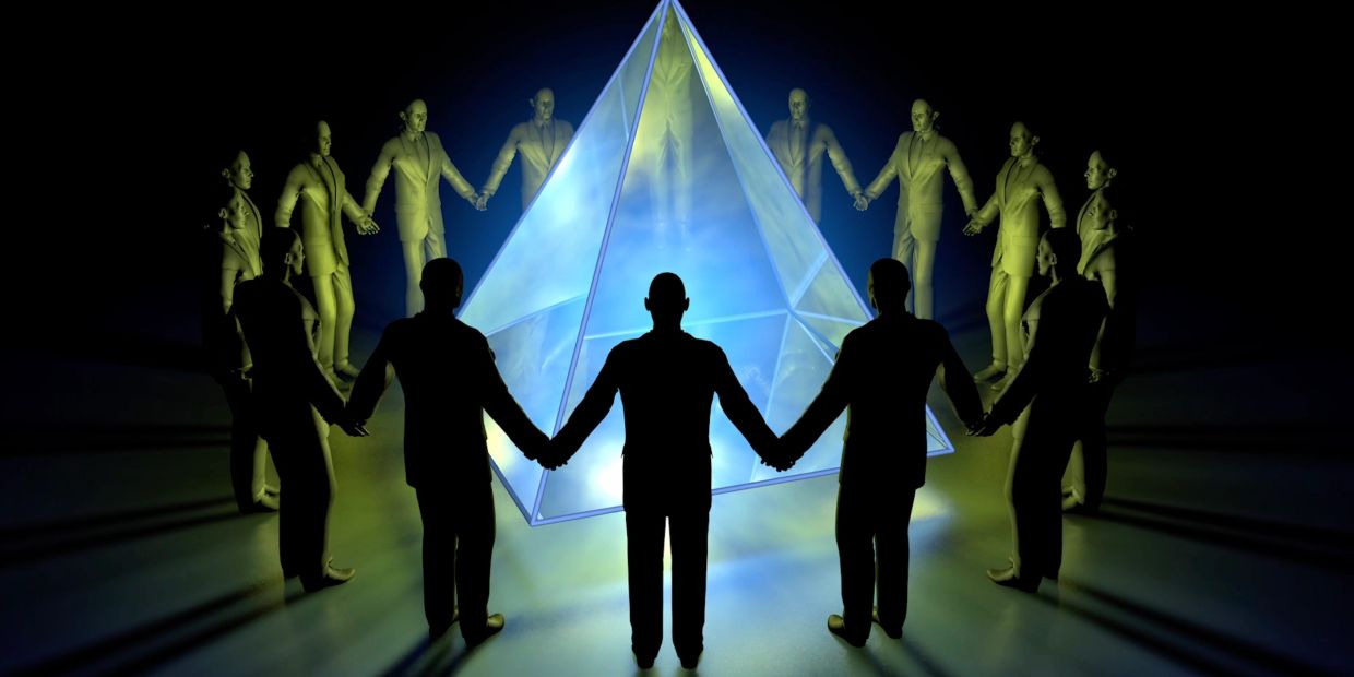 People holding hands around a glowing pyramid.