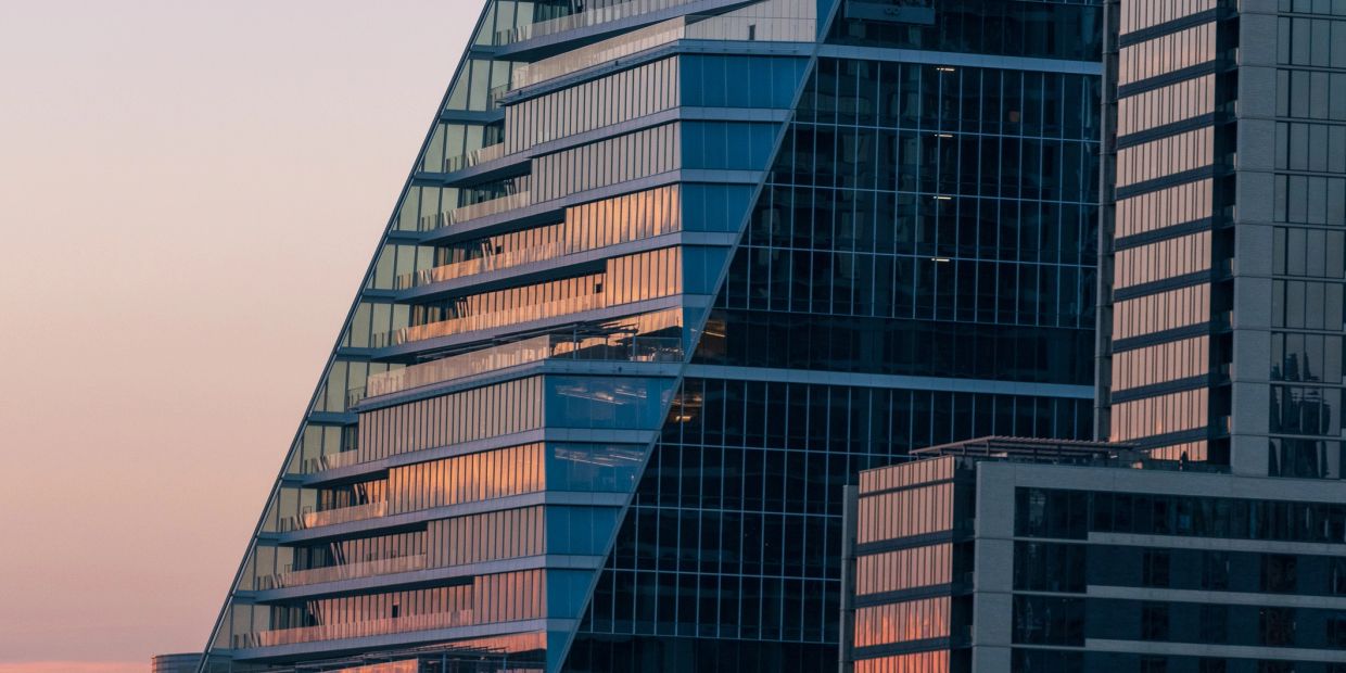 Modern glass skyscrapers reflecting the sunset.