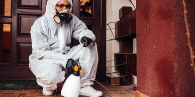 Person in protective gear preparing a spray bottle for disinfection.