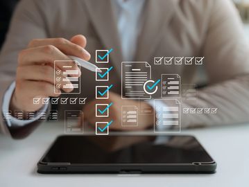 Person using a stylus on a tablet with digital checklist icons overlaid.