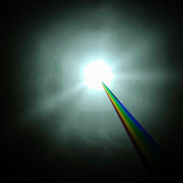 Bright light emitting a vibrant rainbow beam into the dark sky.