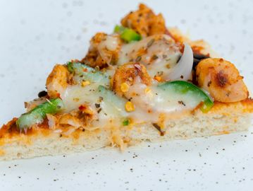 A slice of pizza topped with chicken, green peppers, onions, and melted cheese.