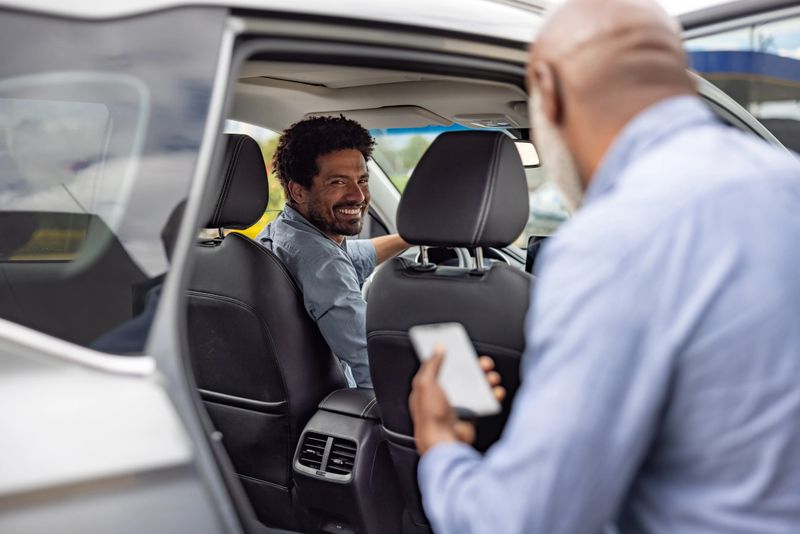 African American crowdsourced taxi driver picking up a passenger and smiling - mobility as a service concepts