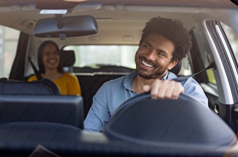 appy crowdsourced taxi driver talking to a female passenger in the back seat and looking through the rear view mirror