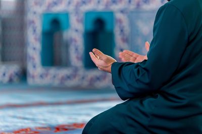 Person praying with hands raised indoors.
