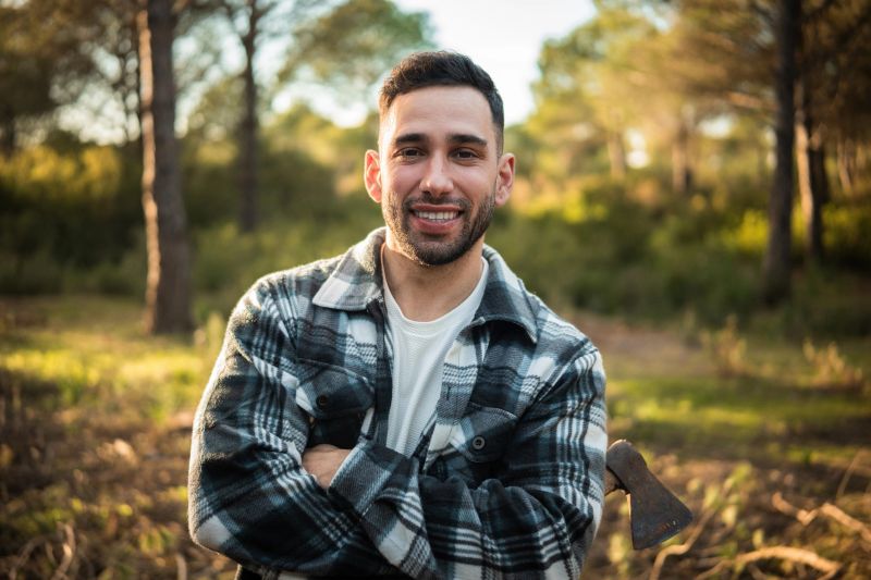 Portrait of a lumberjack smiling with his axe in the forest
