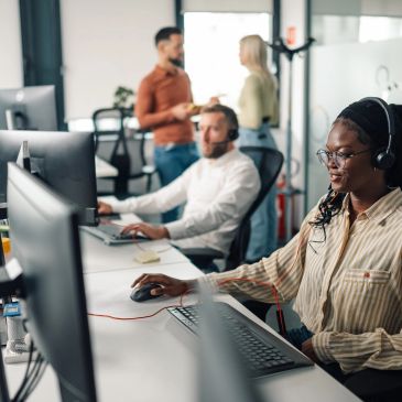 Call center employees working with headsets in a modern office.