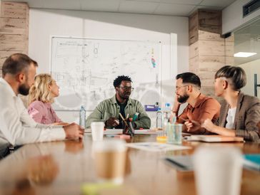 A diverse team is engaged in a collaborative meeting around a conference table.