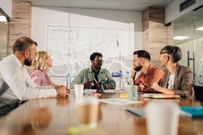 Diverse marketing team discussing and strategizing in modern office, fostering collaboration and innovation