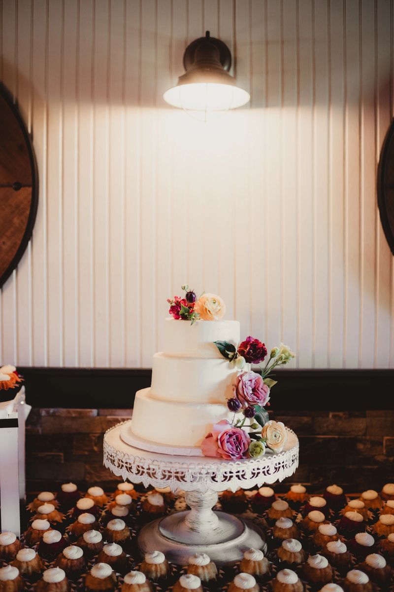 Elegant vanilla wedding cake with flowers and mini cupcakes