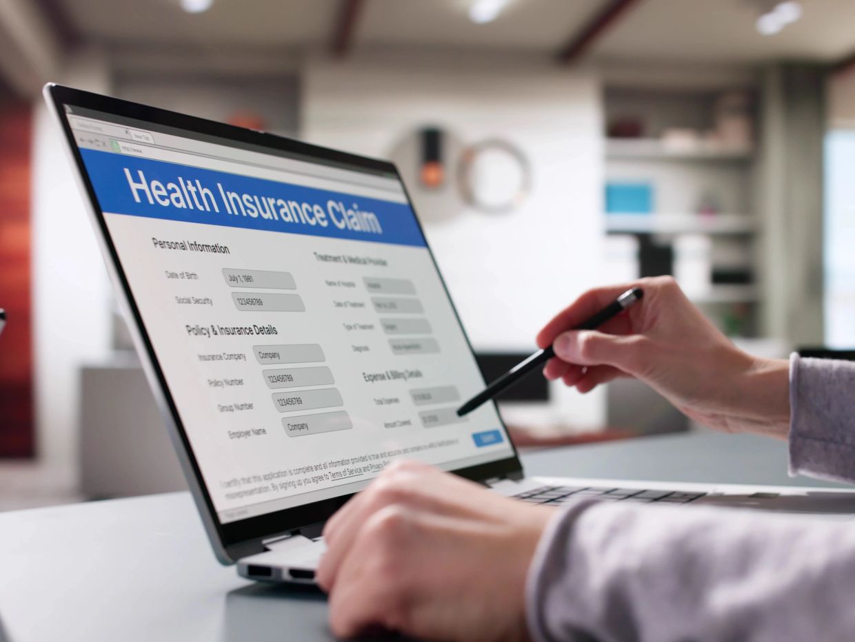 Person working on a health insurance claim form on a laptop.