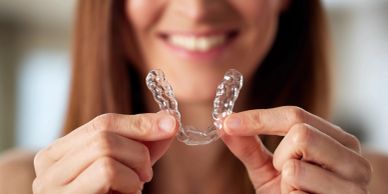 Woman holding a clear dental aligner smile.