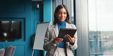 Confident businesswoman using a tablet in a modern office near a window.