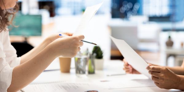 Two people reviewing documents at a bright office desk.