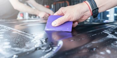 Person using a purple tool to smooth a surface covered in liquid.