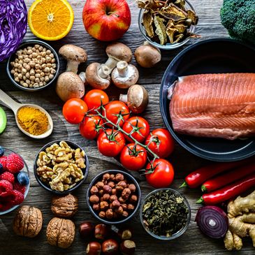 Fresh and healthy ingredients including salmon, tomatoes, nuts, and spices on a wooden table.