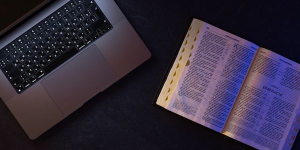 Laptop and an open book on a dark surface.